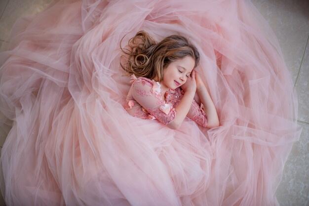 Описание: Encantadora niña en vestido rosa se ve preciosa mientras duerme en el piso | Foto Gratis