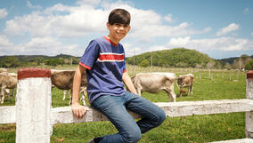 Portrait Of Happy Boy In Farm With Cows In Ranch Stock Photo - Download Image Now - iStock